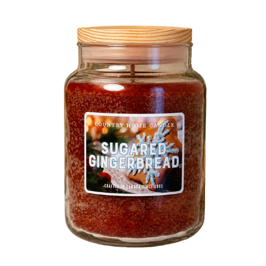 A large glass jar candle with a light wood lid, filled with reddish-brown wax and featuring a front label that reads 'Country Home Candle Sugared Gingerbread'.
